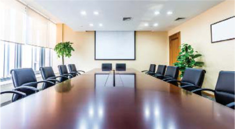 A ritzy boardroom with a projetor screen taking center stage and reflected on the gleaming top of the boardroom table
